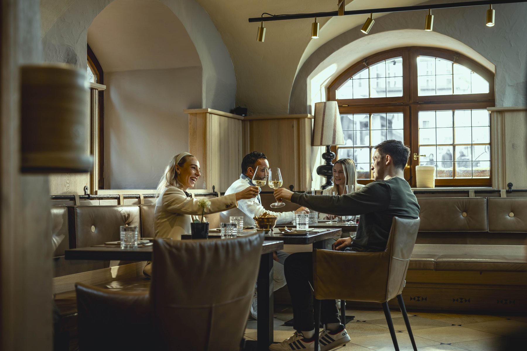 Lifestyle-Fotografie im Restaurant: Gäste stoßen in gemütlichem Ambiente an – authentische Restaurantfotografie für Marketing und Social Media.