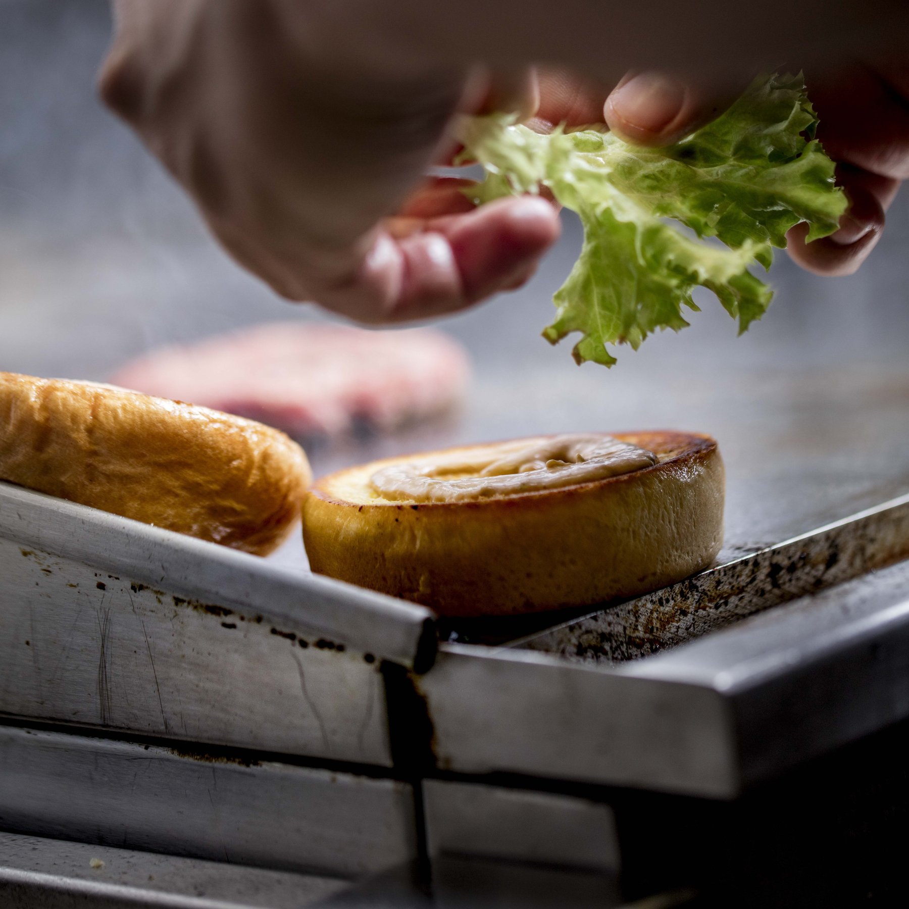 Anrichten von Burger-Spezialitäten mit frischen Kräutern