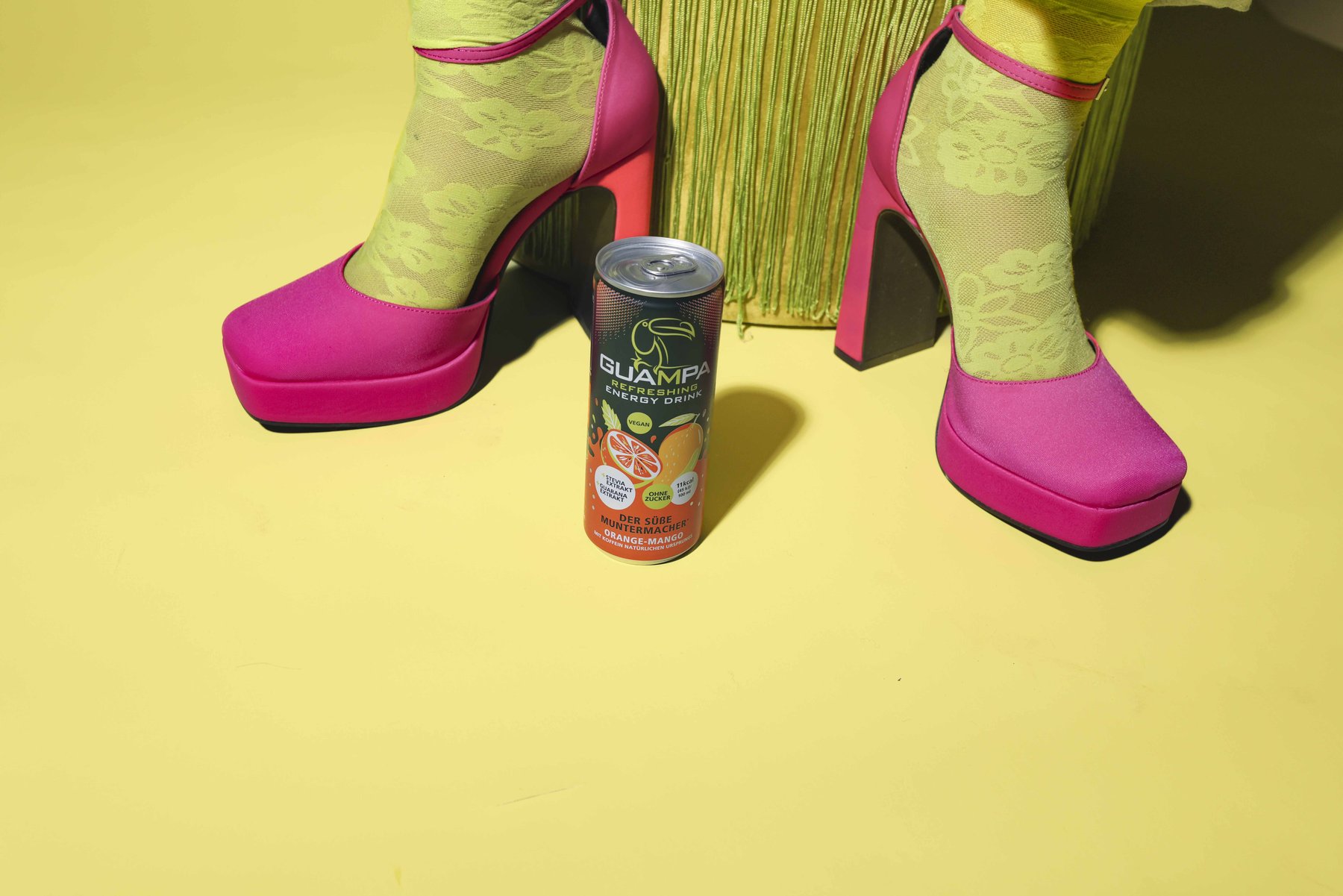 Guampa Energy Dose mit pinken High-Heels auf Gelb – kreative Produktfotografie