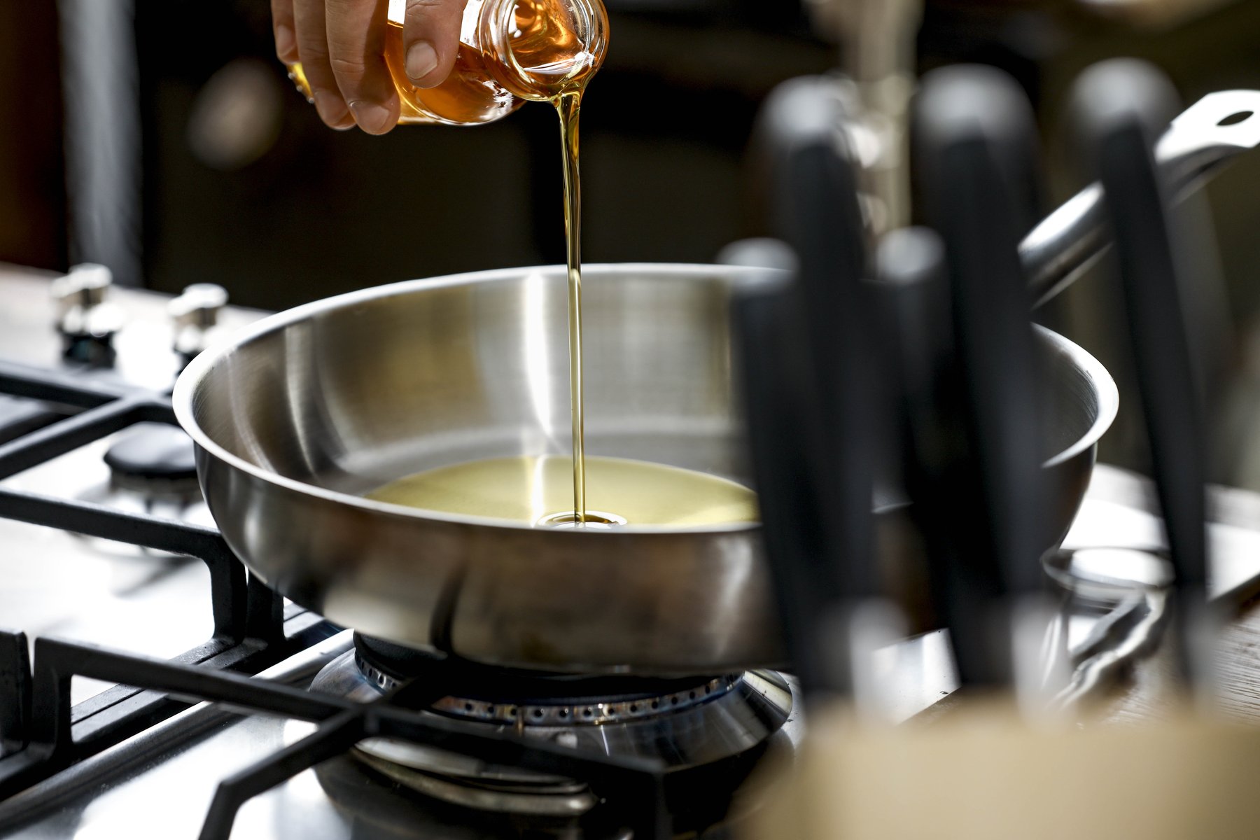 Dynamisches Pouring von Speiseöl in der Pfanne – Werbefotografie mit Fokus auf Glanz und Produktqualität.