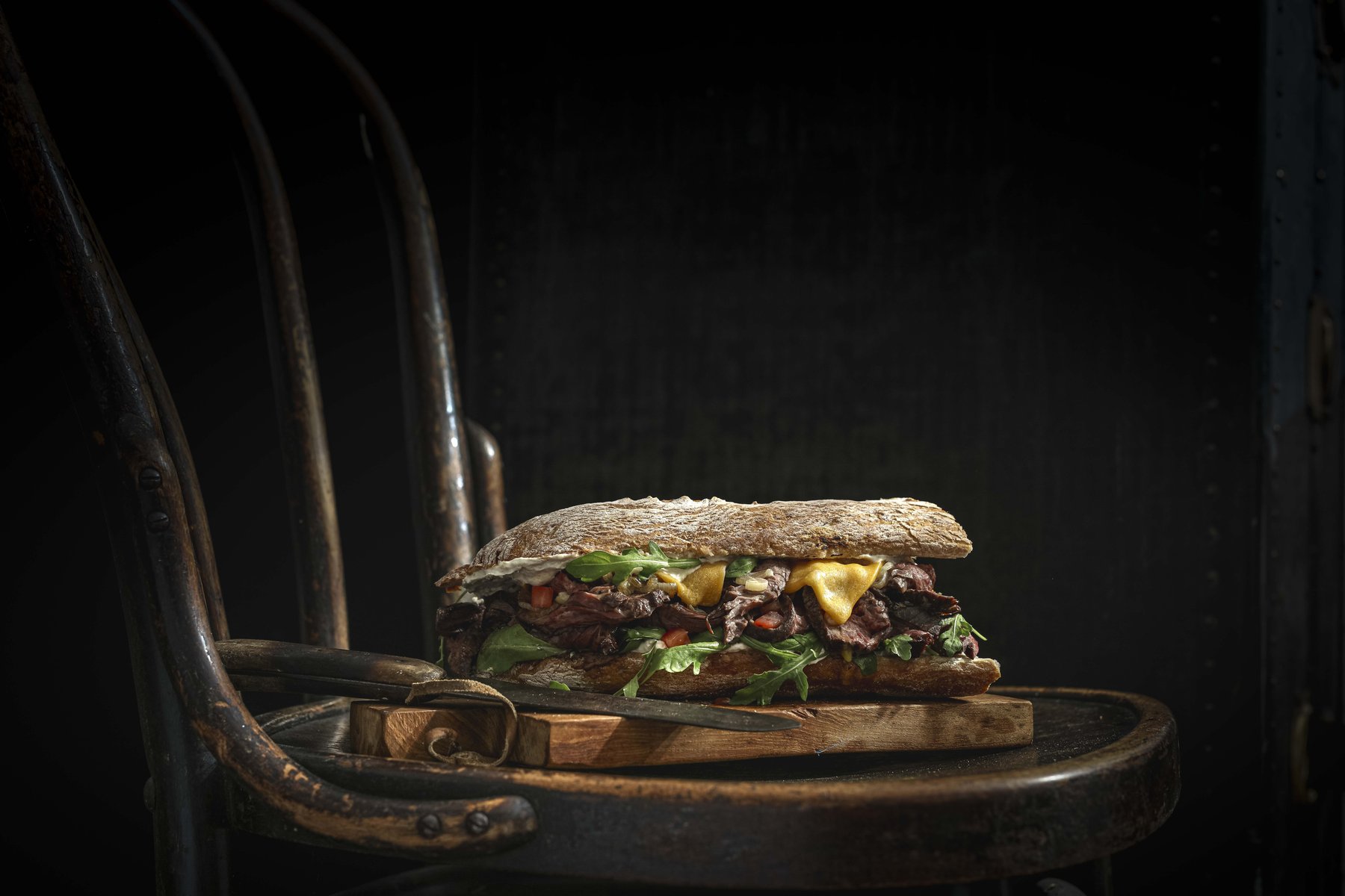 Professionelle Burger-Fotografie: rustikale Inszenierung eines Gourmet-Sandwichs für Marketing und Online-Shops.