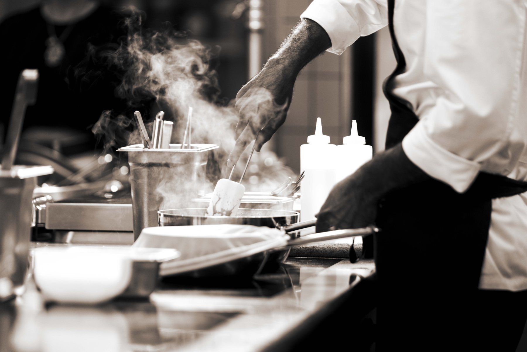 Action-Shot aus der Profiküche in Schwarz-Weiß – authentische Gastronomie-Reportage, Handwerk und Dynamik.