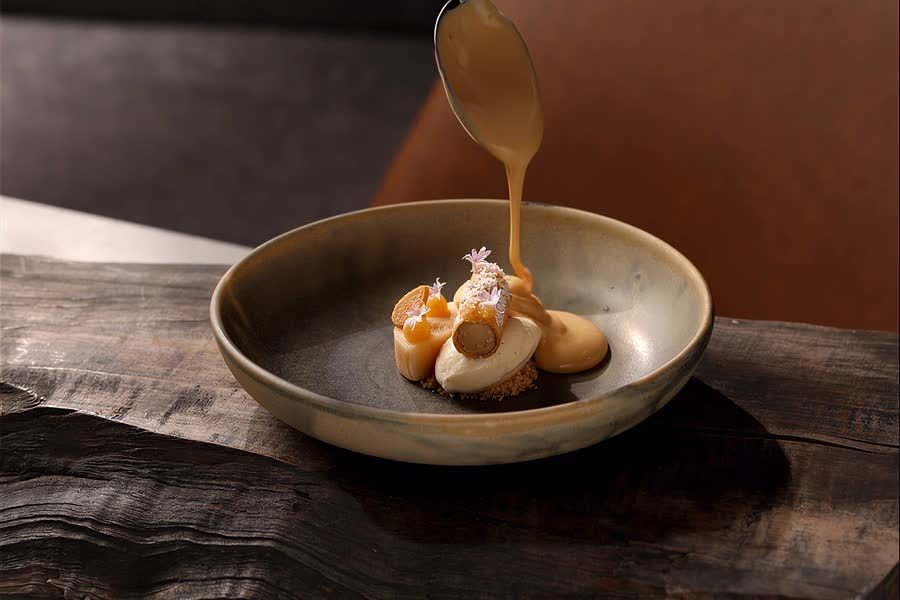 Pouring-Shot: Sauce über einem Gericht in dunkler Schale